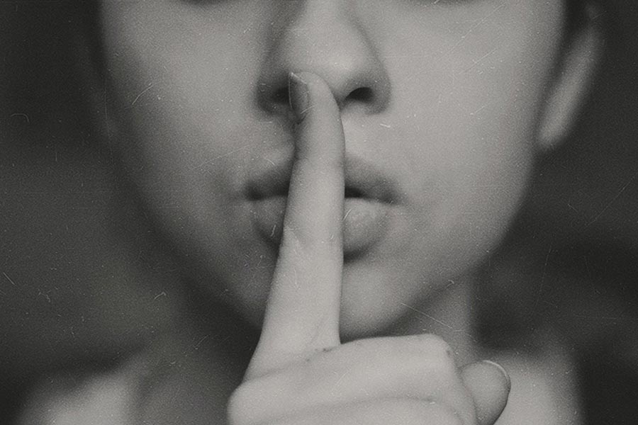 Photo of a woman with her finger over her mouth saying Shh